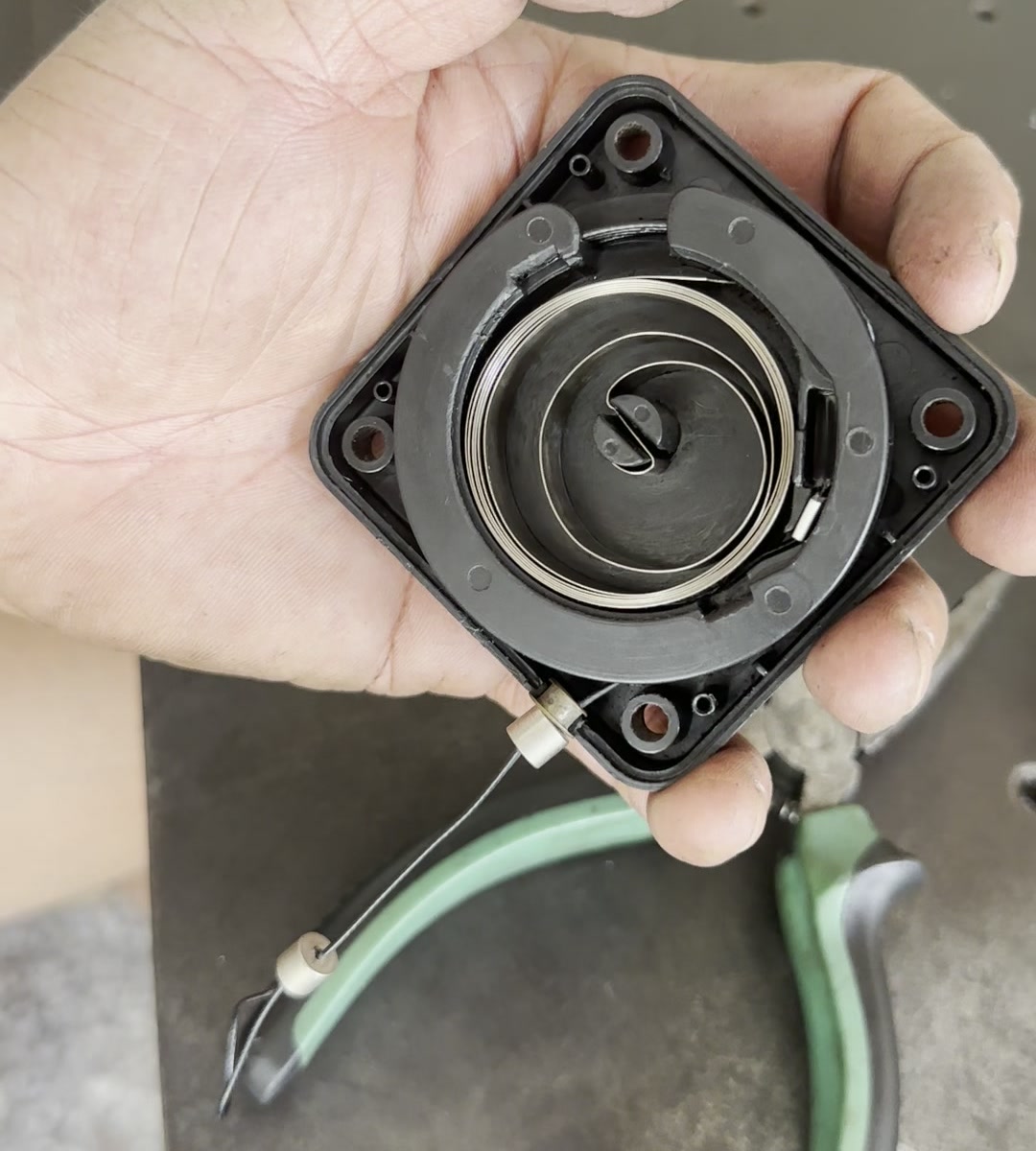 Coiled strip spring and central hub inside an open cord retraction housing, with the cord outlet visible.